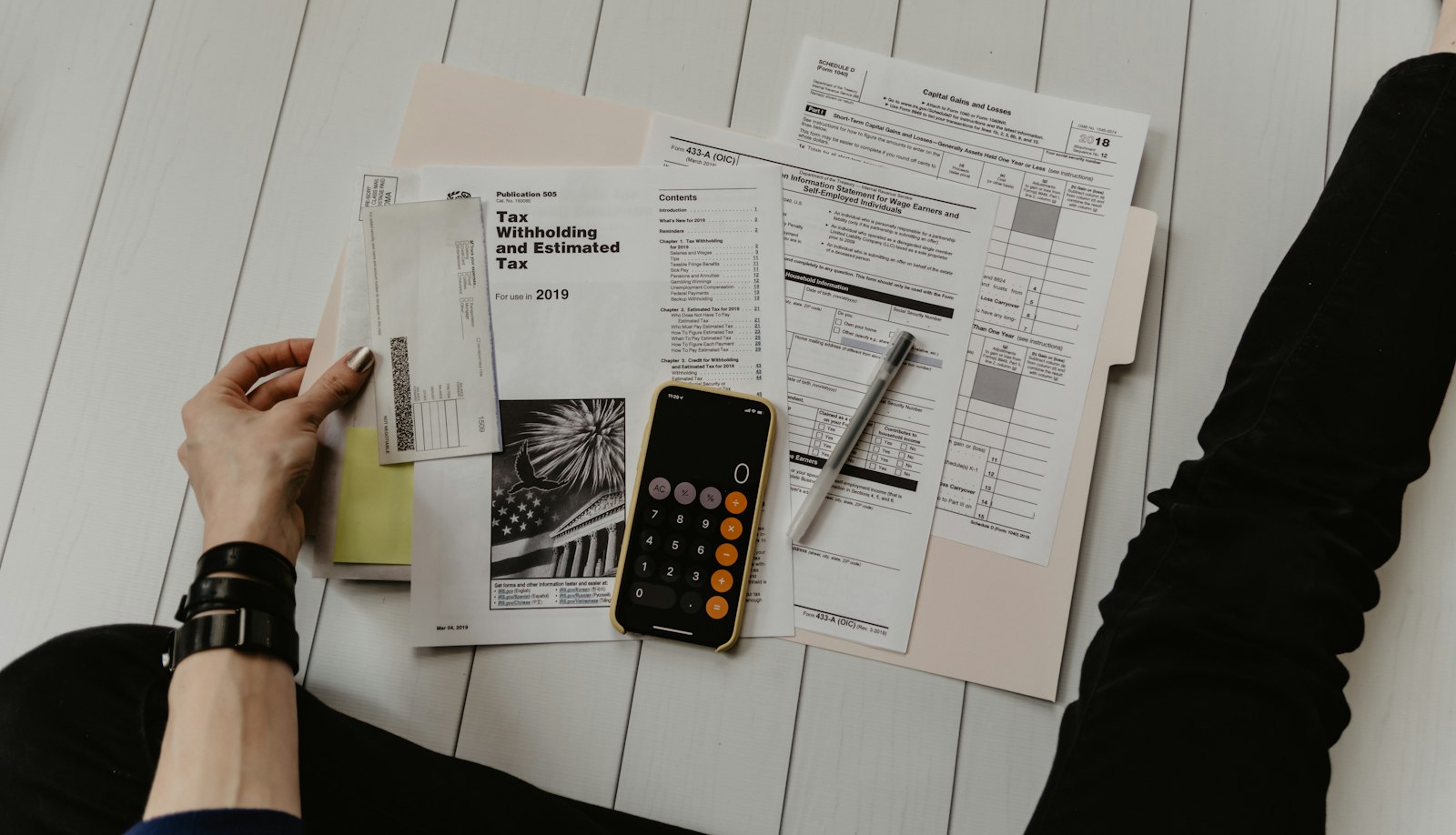 Hands working through invoices and a calculator on a desk